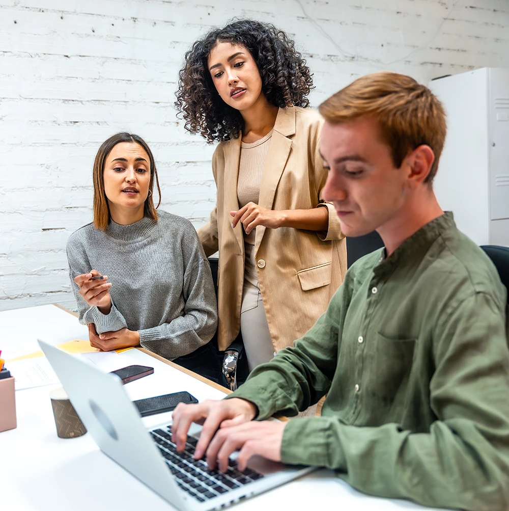 three-diverse-coworkers-using-laptop-and-discussing